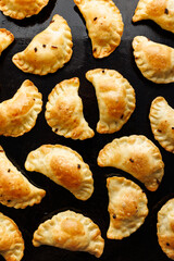 Homemade baked dumplings on a black background, top view