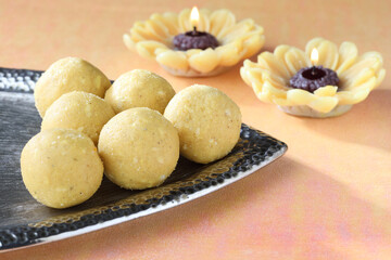 Indian festival diwali sweet motichur laddu serve in a decorative silver plate with colourful lamps