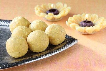 Diwali Sweets besan Laddu Indian traditional sweet served in a decorative silver plate along with lamps or candles