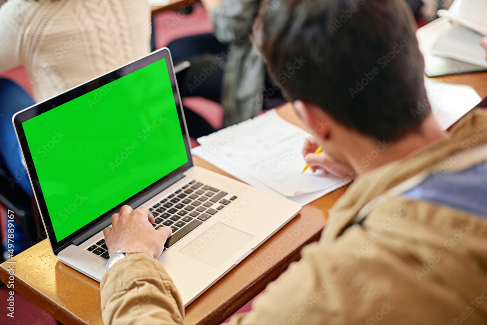 Poster using tech to further his education. overhead shot of a student using his laptop at his desk in clas