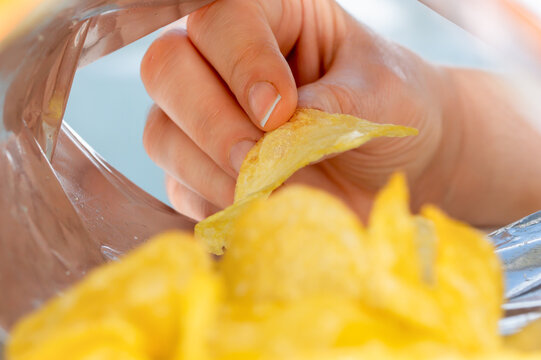 Hand holding potato chips inside snack foil bag