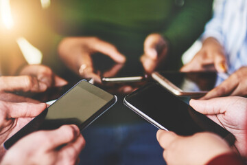 Instantly connected. Cropped shot of a group of people using their phones together.