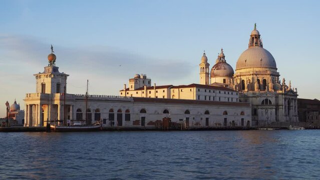 Venice Italy sailing during sunrise on the calm waters of Grand Canal with Basilica di Santa Maria della Salute and Punta della Dogana at Dorsoduro district visible.