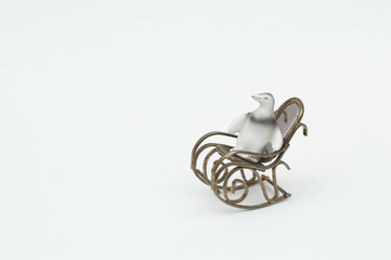 Fototapeta na wymiar Miniature silver rocking chair with a small porcelain penguin