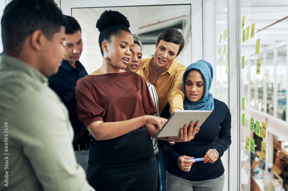 Poster Technology helps them better understand their big plans. Shot of a group of businesspeople using a digital tablet while brainstorming with notes on a glass wall in an office.