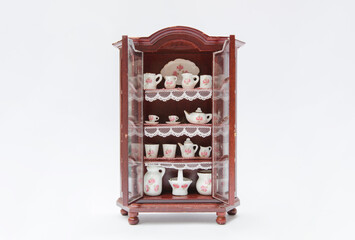 Vintage miniature cupboard isolated with open doors and porcelain dishes
