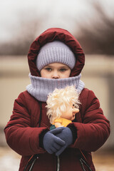 Portrait of a little girl with a sad look and a toy in her hands. The social problem of refugees...