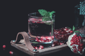 two colorful summer cocktails with pomegranate and mint on a black table