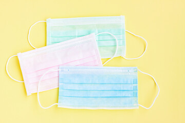 Multicolored surgical masks on yellow background