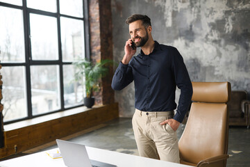 Smiling successful contemporary man manager in casual wear holding phone call. Happy inspired...