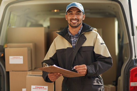 Deliveries are right on schedule. Portrait of a smiling delivery man standing in front of his van holding a package.