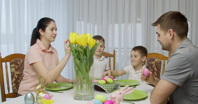 family sit at the holiday table, clash colorful eggs. easter dinner
