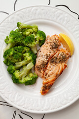 White plate with grilled salmon served with broccoli and lemon. Healthy food for family. Home dinner. Vegetarian diet diet.
