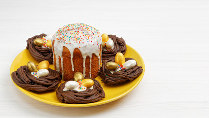 Homemade Easter cake decorated with candies in the form of Easter eggs on white wooden table. Copyspace.