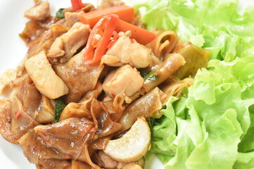 spicy fried large rice noodles with chicken and slice mushroom on plate