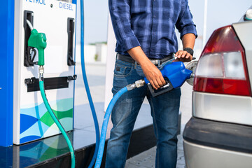 young man self refueling car at petrol or gas filling station after paying from mobile - concept of...