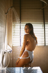 Sensual portrait of passionate beautiful young Asian woman taking a shower and looking at camera in...