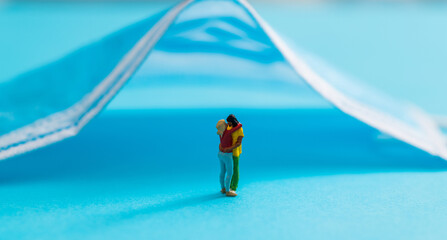 Medical mask and couple figurine on blue background
