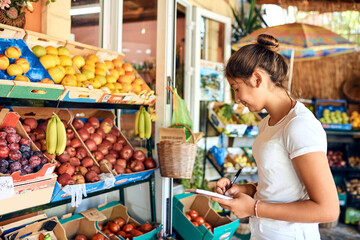 Taking stock. Cropped shot of an attractive young woman working at a farm stall.