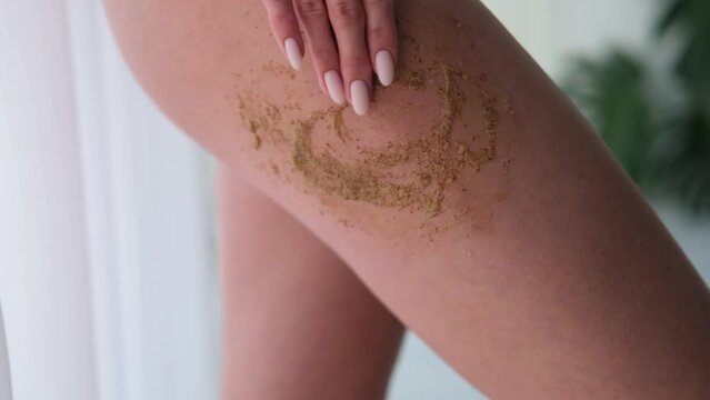 A woman applies scrub on her legs. Women use anti-cellulite cream. female body care. Cosmetology, massage, spa cosmetics.