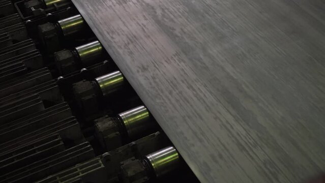 The metal sheet goes along the conveyor line in close-up. Metallurgical plant. Production of rolled metal at a metallurgical factory.