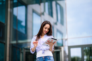 Happy business woman using tablet pc in front of office building