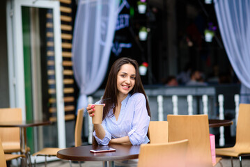 Fototapeta na wymiar Pensive happy woman sipping a milkshake in the street