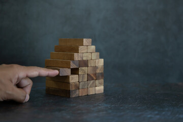 Hand place wooden block stack in pyramid stair step concept of prevent collapse or crash of...
