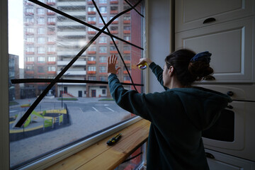 Young woman sealing the window glass using adhesive tape