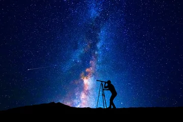 Fotobehang Man die door een telescoop naar de sterren kijkt © quickshooting