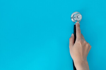Hand holding a stethoscope on blue background