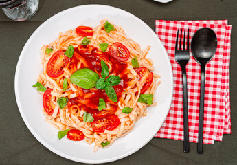 Top view of a plate of spaghetti pasta with a delicious tomato sauce with basil leaves. Natural and homemade food concept.