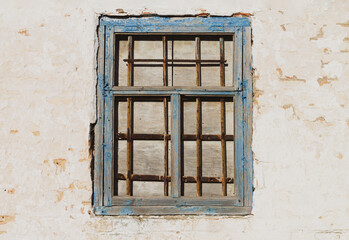 Old wall and closed wooden window with rust grille