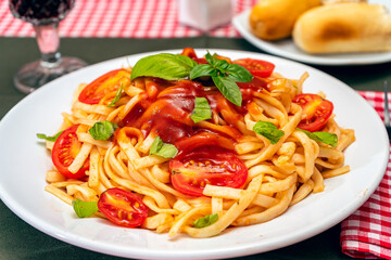 High view of a plate of spaghetti pasta with a delicious homemade tomato sauce with homemade basil leaves. Homemade and natural food concept.