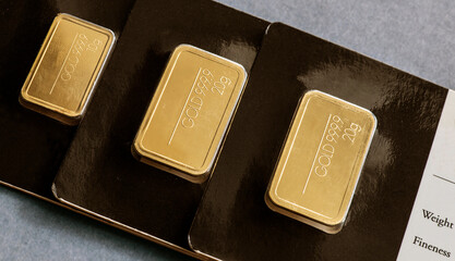 Several minted gold bars of different weight in plastic packaging.