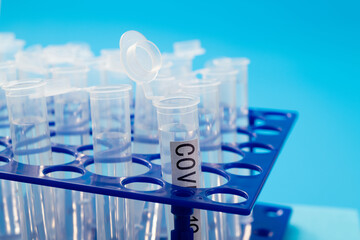 Test tube with word COVID-19 on blue background