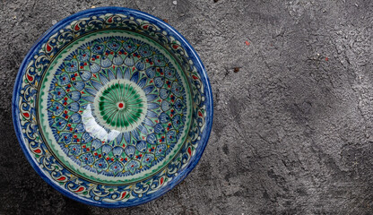 hand painted blue ceramic dish, traditional Uzbek utensils dishes, bowl, plates with national floral ornament on dark background, Long banner format. top view