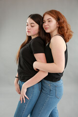 two beautiful girls on a gray background. girlfriends hugging. red hair color. studio photo shoot. female friendship. stop the war