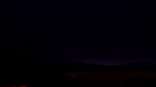 Time lapse of night is falling over rural landscape with lavender fields and mountains. Puimoisson region, Plateau Valensole, Alpes de Haute Provence in France.