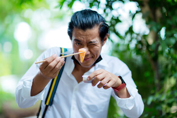 man holding Salmon sashimi on chopsticks