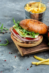 burger with ham, cheese, bacon, salad and vegetables. Big burger, american fast food. vertical image. top view. place for text