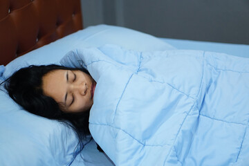 asian women lying on the bed with blue blankets    