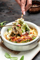 hot spinach crepes or pancakes with chicken and mushrooms baked with cheese. cooking concept, vertical image. top view