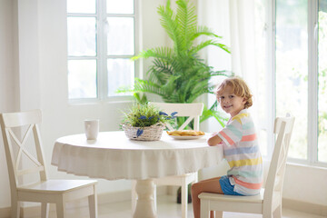 Kids eating breakfast in white kitchen.