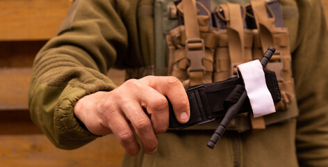 A military man holds a medical tourniquet in his hands to stop blood in first aid and prevent bleeding. Combat tactical equipment. Combat use Turnstile.