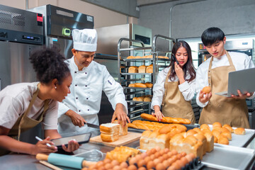 Cooking  course , senior Asian male chef in cook uniform teaches young asian and african american people cooking class students to prepare, mix ingredients for pastry foods, in restaurant stainless 