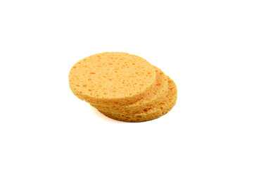 Three round yellow facial sponges lie one on one isolated on a white background.