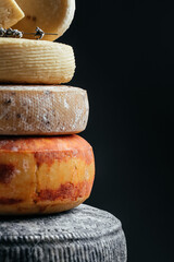 Various kind of cheese. head of handcrafted hard cheese on a dark background. vertical image. top...