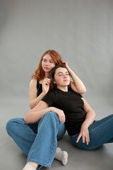 two beautiful girls on a gray background. girlfriends hugging. red hair color. studio photo shoot. female friendship. stop the war