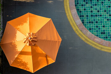 An open parasol by the swimming pool at sunset. - obrazy, fototapety, plakaty
